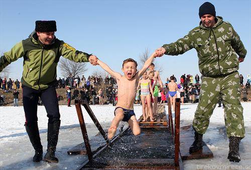 Православно дете го бањаат во ледена вода на празникот Богојавление во близина на Бишкек, Киргистан
