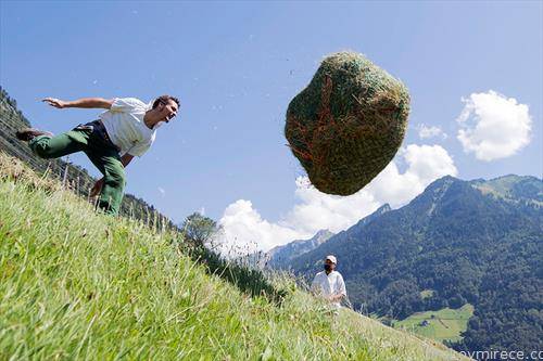 човек кој фрла топки од сено, учествува на фестивал, во Швајцарија