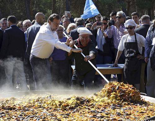 Премиерот  на Шпанија и лидер на Народната партија Мариано Рахој му помага на готвачот во подготовката на палеа