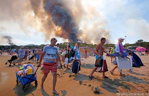 туристи ја напуштаат плажата на францускиот брег  од Медитеранот, поради големиот пожар