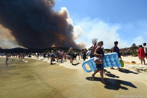 туристи ја напуштаат плажата на францускиот брег  од Медитеранот, поради големиот пожар