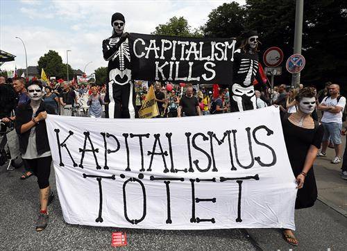 Демонстранти со натписи Капитализмот убива маршираат на протест во текот на Г-20 самитот во Хамбург