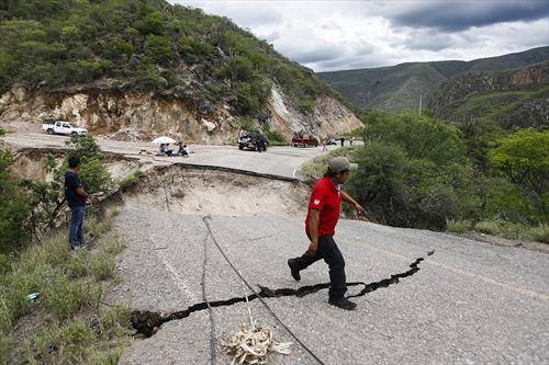 Човек поминува преку  растурен автопат, во Мексико,