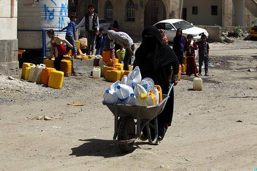 Жена во Јемен турка количка со шишиња наполнети со безбедна вода за пиење од дониран цевковод во Сана.