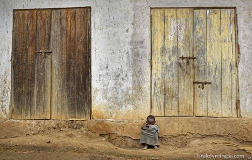дете од село во Уганда пред вратите од неговиот дом