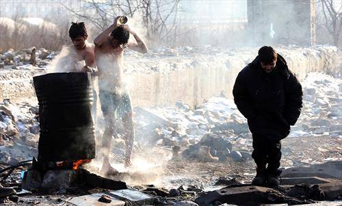 Мигранти се бањаат на отворено пред напуштено складиште во Белград