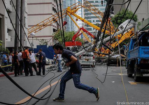 Филипинец брза да мине крај искинатите кабли по колапсот на градежен кран во градот Макати