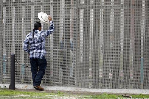 Човек зборува со роднина на оградата на граница меѓу САД и Мексико,