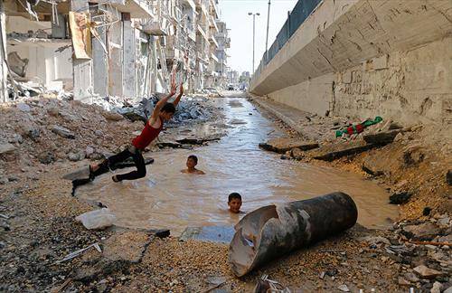 деца во Алепо Сирија се разладуваат во кратер од бомба